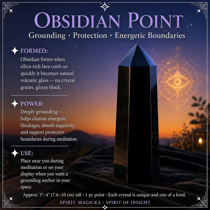 A tall, glossy black obsidian point with a faceted tip standing on black velvet at dusk
