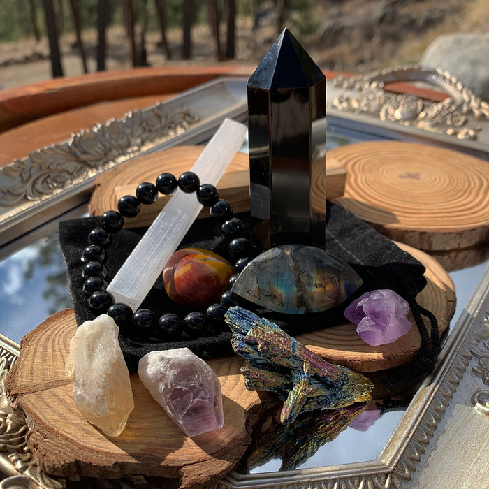 A past box with a black obsidian tower, a selenite stick, a black bead bracelet, raw amethyst and smoky crystals