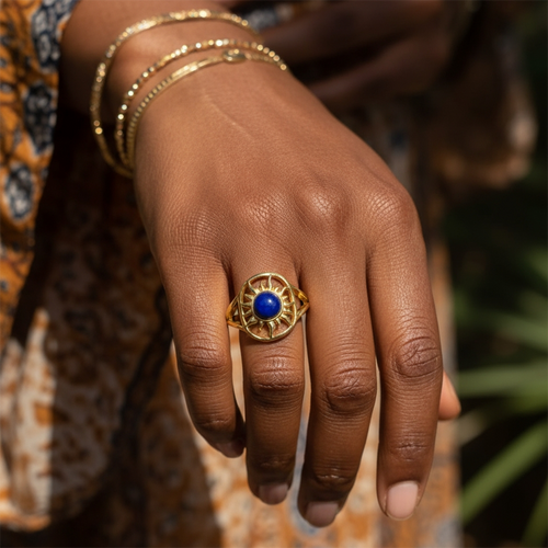 The solar wisdom ring worn on the ring finger, its blue lapis and gold sunburst sitting across the finger