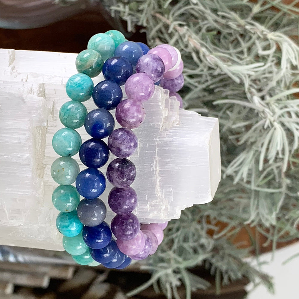 Lepidolite, blue aventurine and amazonite bead bracelets stacked on a selenite tower