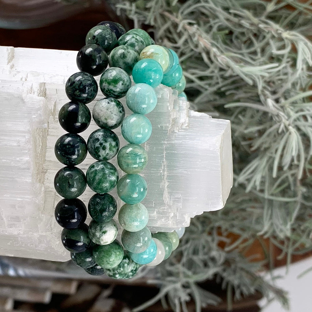 Moss agate, green spot jasper and amazonite bead bracelets stacked on a selenite bar