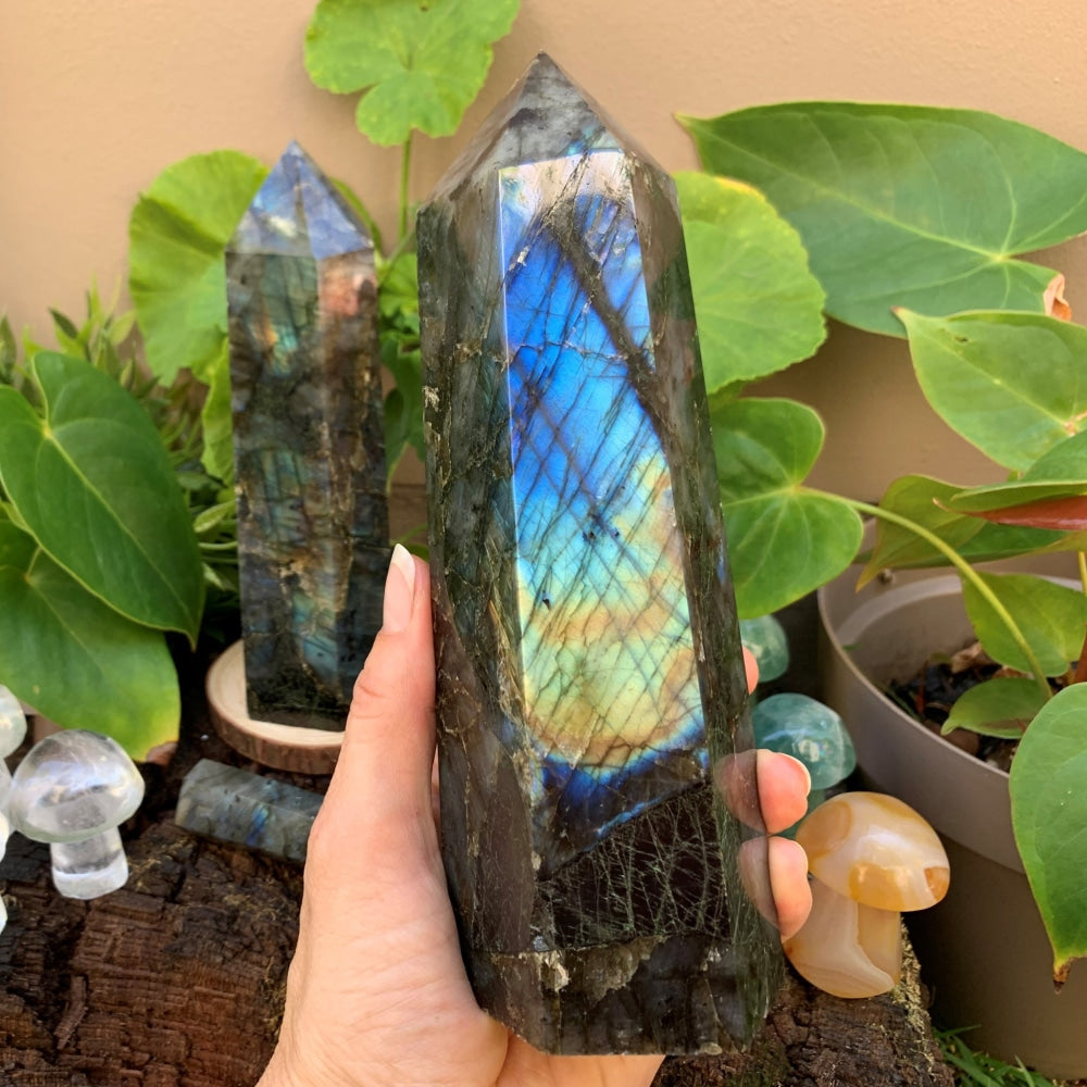 A large labradorite generator held in one hand, its face flashing electric blue and gold