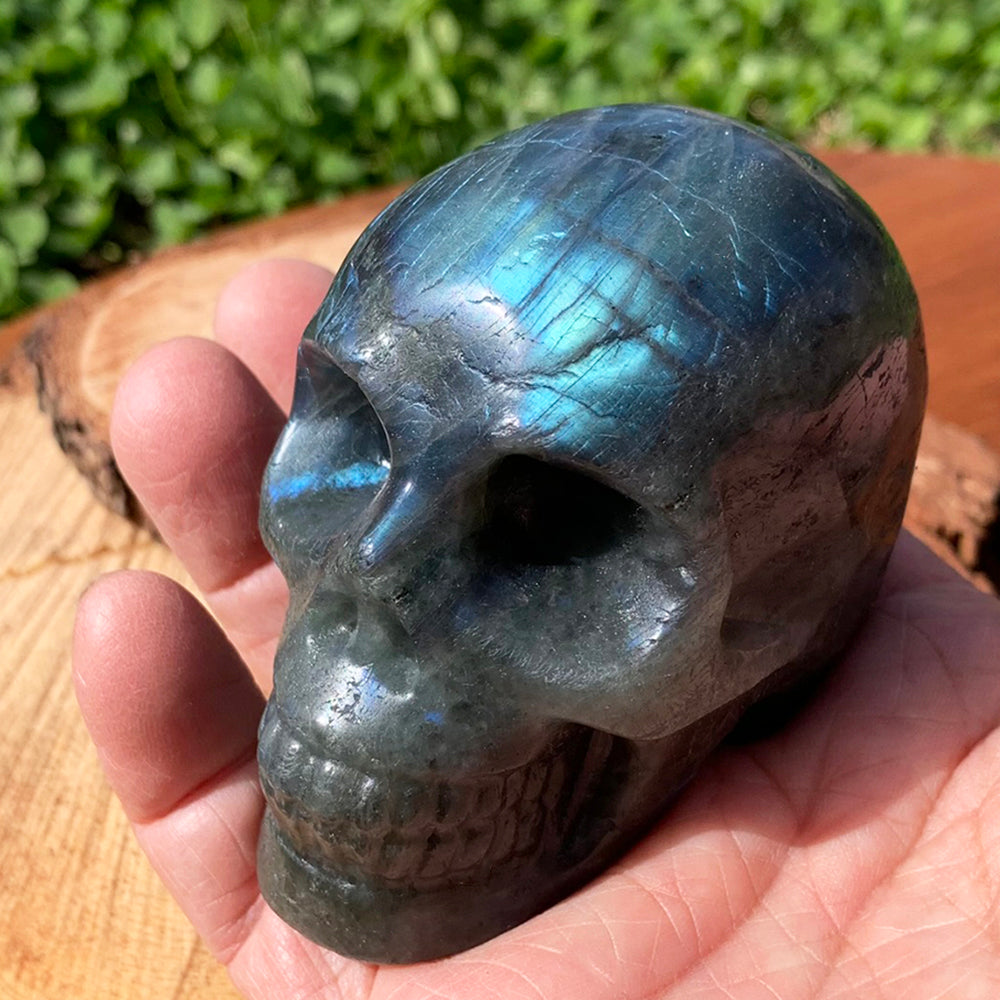 The labradorite skull resting in an open palm, filling the hand