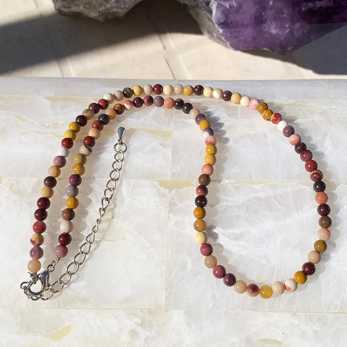 Mookaite jasper beaded necklace in red, cream and mustard tones on a selenite slab