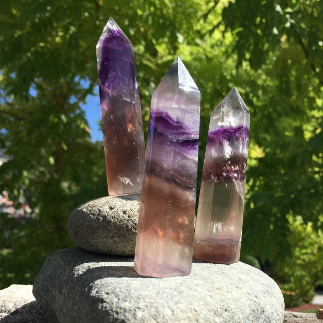 Three multicolor fluorite points standing on stacked stones, each banded differently