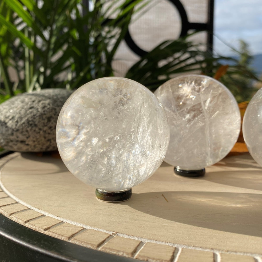 A clear quartz sphere catching the sun on a round tabletop, with soft white veils inside