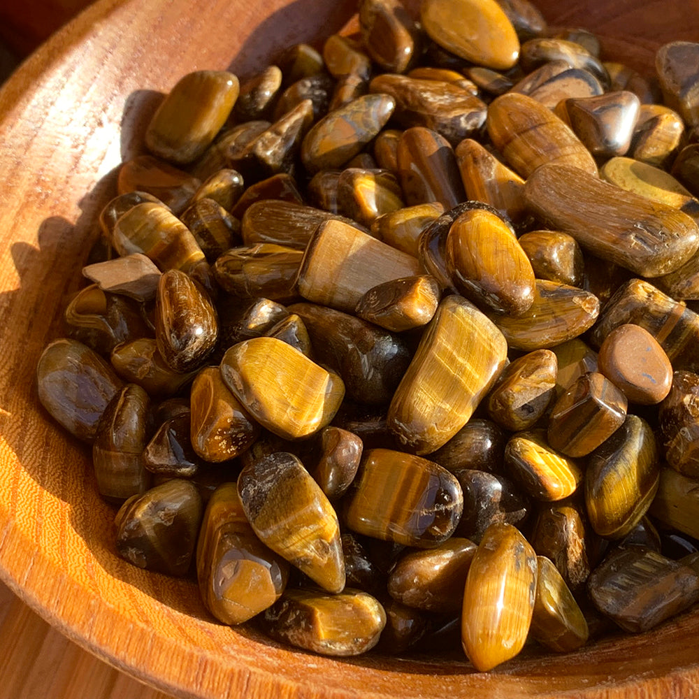 Close-up of sunlit tiger’s eye mini gemstones with golden-brown bands that shimmer as the light catches them
