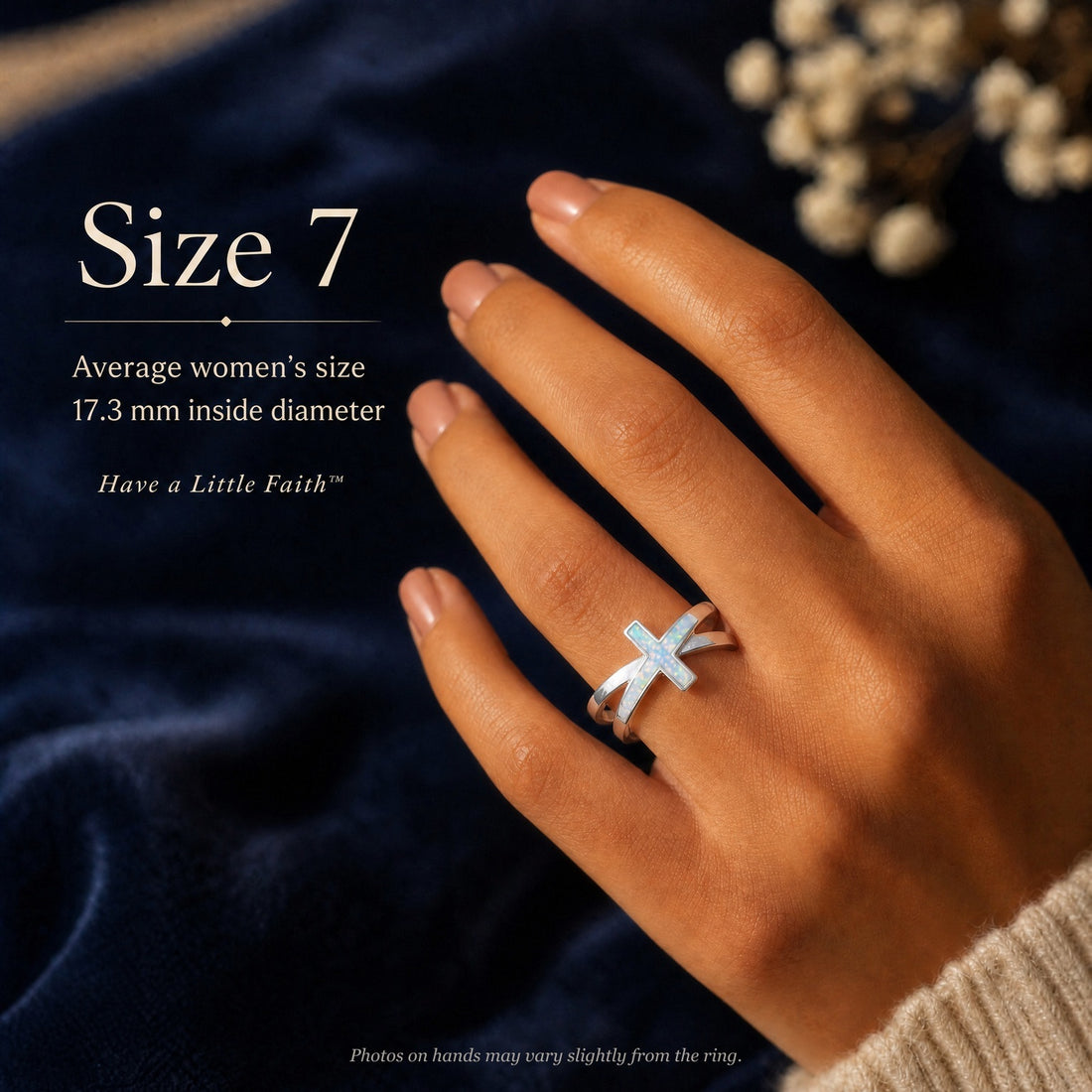 A hand wearing the opal cross ring in size 7 against dark blue velvet